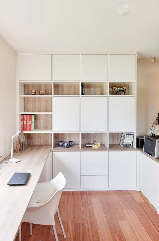 a functional Scandinavinhome office with white and stained storage units, with a built-in desk and some pretty decor is very chic
