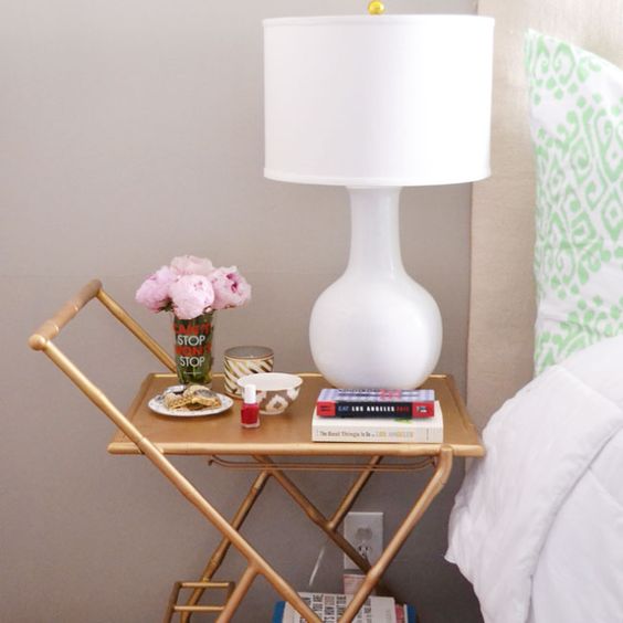 a gold cart with casters and tiered shelves is a shiny and cool idea for a modern bedroom, it can be a nice idea with a glam feel