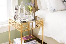 a gold metal and glass tiered side table as a chic and glam nightstand adding a bit of bling and eye-catchiness to the space