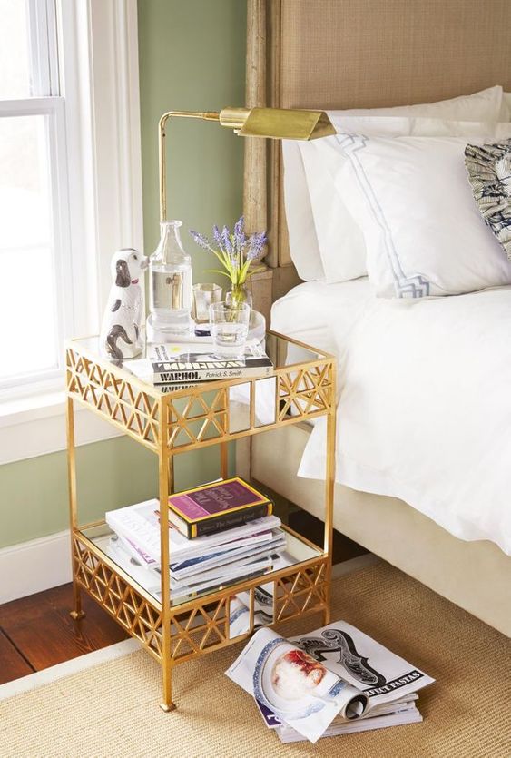 a gold metal and glass tiered side table as a chic and glam nightstand adding a bit of bling and eye catchiness to the space