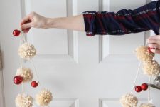 a gorgeous holiday garland of white pompoms and red ornaments to decorate your Christmas tree