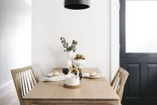 a laconic Nordic dining room with a sleek stained table and chairs, a black pendant lamp and greenery is super cool