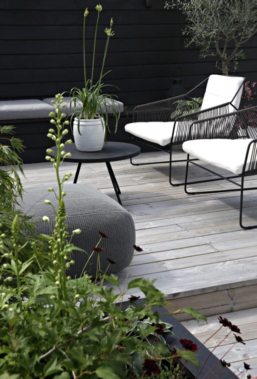 a laconic Nordic terrace with an upholstered bench, black and white chairs, a black coffee table and a grey pouf a laconic Nordic terrace with an upholstered bench, black and white chairs, a black coffee table and a grey pouf