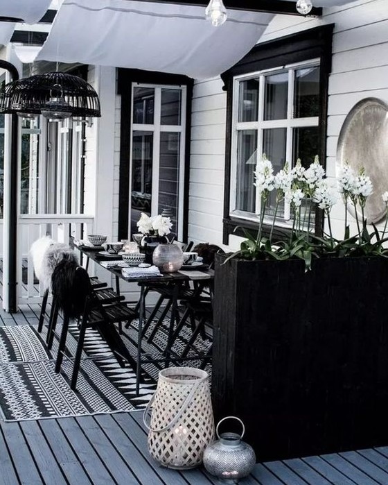 a laconic Scandinavian dining space with black furniture, a tall planter as a space divider, candle lanterns and pendant lamps a laconic Scandinavian dining space with black furniture, a tall planter as a space divider, candle lanterns and pendant lamps