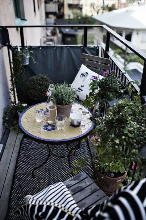 a monochromatic balcony with chairs and a lot of potted greenery is spruced up with a colorful mosaic table