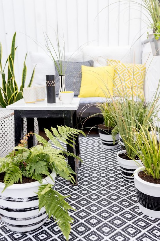 a monochromatic balcony with printed textiles, potted greenery and succulents and simple and stylish furniture