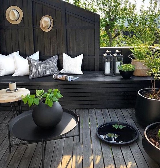 a moody terrace with black wood, light pillows, potted greenery and candle lanterns looks fresh and stylish a moody terrace with black wood, light pillows, potted greenery and candle lanterns looks fresh and stylish
