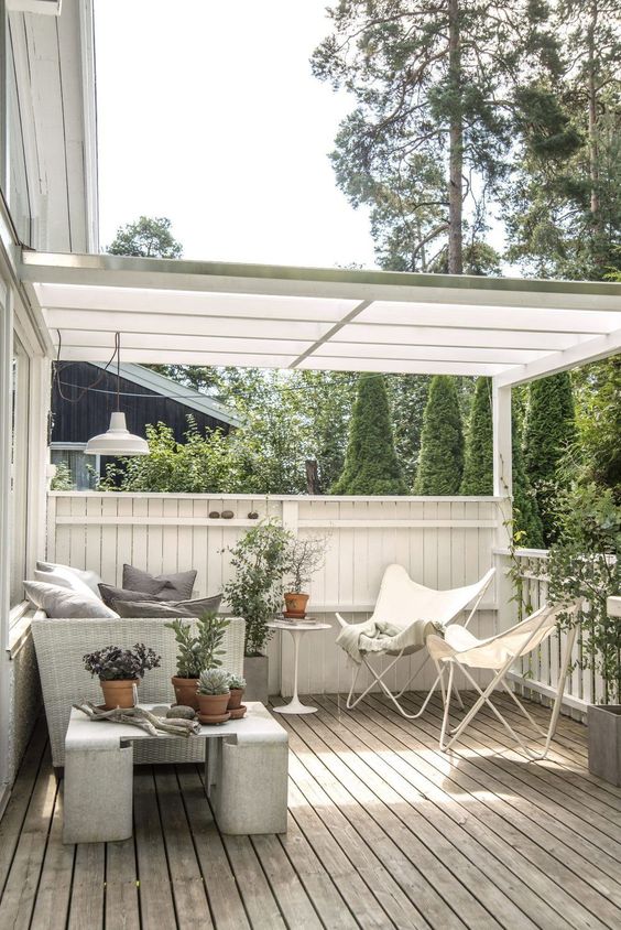 a neutral Scandi terrace under a roof, with a wicker sofa, white butterfly chairs, a concrete side table, potted greenery a neutral Scandi terrace under a roof, with a wicker sofa, white butterfly chairs, a concrete side table, potted greenery