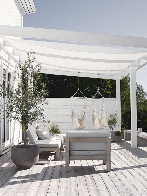 a neutral Scandinavian terrace with neutral upholstered furniture, hanging chairs, potted plants and blankets is super welcoming a neutral Scandinavian terrace with neutral upholstered furniture, hanging chairs, potted plants and blankets is super welcoming