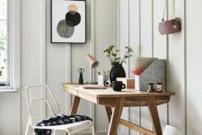 a neutral and welcoming home office with a wooden desk, a basket, a wire chair and some bright stuff on the desk
