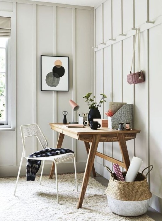 a neutral and welcoming home office with a wooden desk, a basket, a wire chair and some bright stuff on the desk