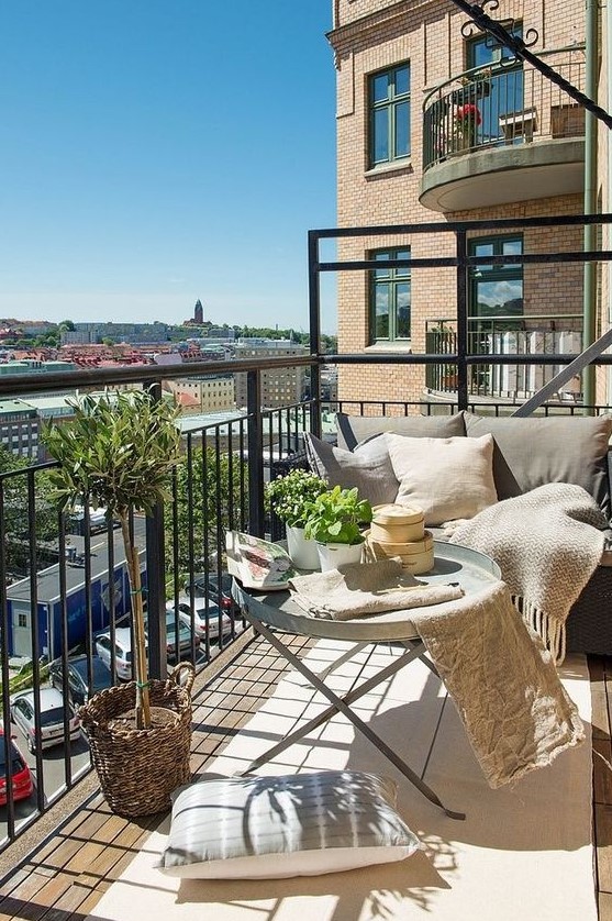 a neutral balcony with metal furniture, neutral textiles, potted greenery and lots of pillows is very welcoming