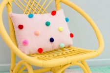 a pink pillow with colorufl pompoms accenting it is a cheerful and bright accessory that you can easily DIY