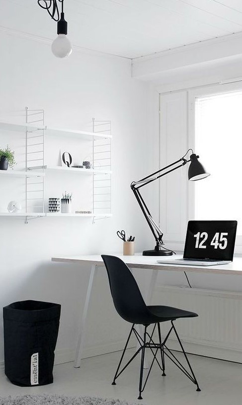 a simple Nordic black and white home office with a white desk, shelving unit, a black chair and a storage fabric basket