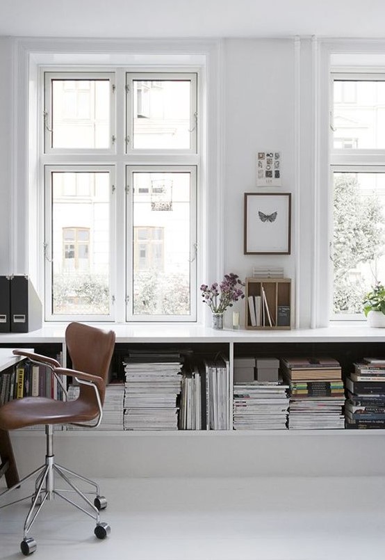 a simple Nordic white home office with a large open storag eunit, a white desk and a brown leather chair