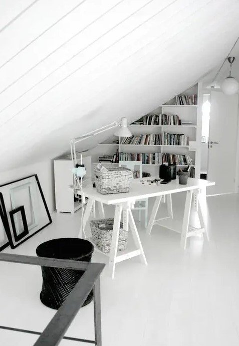 a small Scandinavian home office with a trestle desk, a bookshelf on the wall, some empty frames and a lamp
