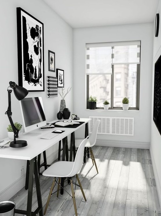 a small Scandinavian home office with a two black and white trestle desks, white chairs and black and white artworks