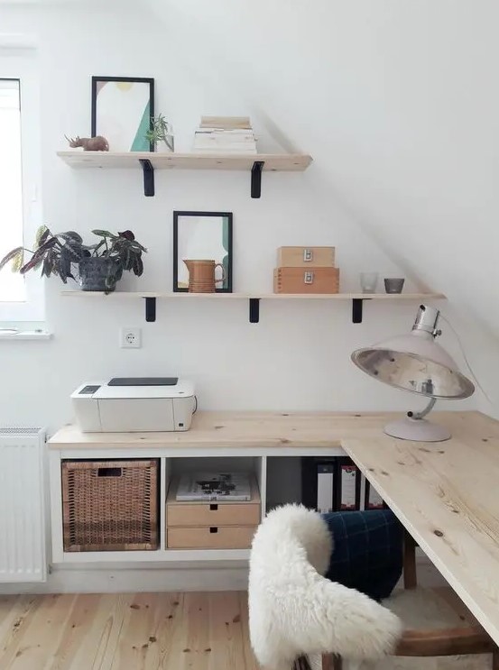 a small attic Nordic home office with floating desk with storage, wall-mounted shelves, cool lamps and a comfy chair