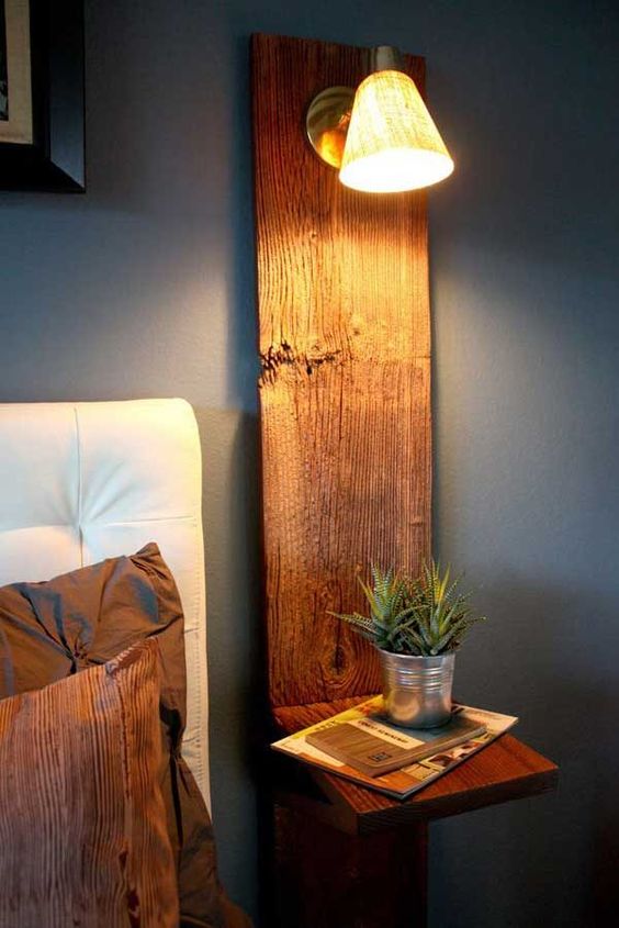 a stained wooden nightstand   a wooden plank attached to the wall and an additional small shelf, a sconce attached and some potted succulents
