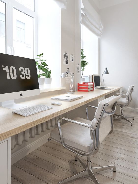 a stylish Scandi home office with a wall-mounted desk, white chairs, table lamps, potted greenery and a touch of red for fun