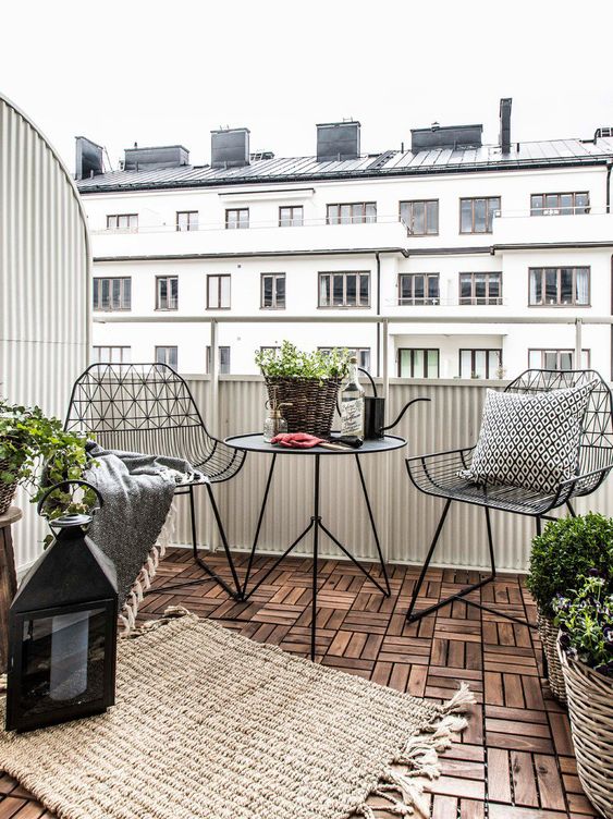 a stylish Scandinavian balcony with black metal chairs and a coffee table, candle lanterns and potted plants is a very stylish idea for a Nrodic style lover