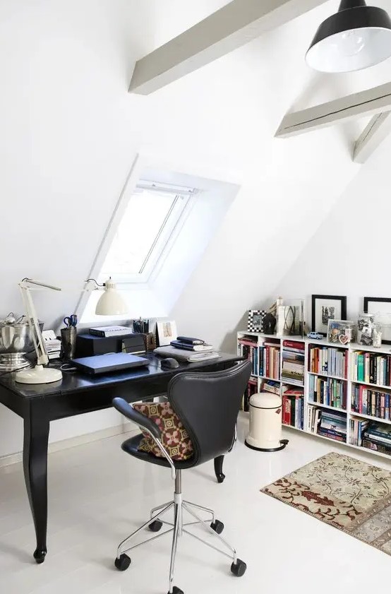 a stylish Scandinavian home office with wooden beams, a vintage black desk, a black leather chair, a large bookshelf, some rugs and pillows