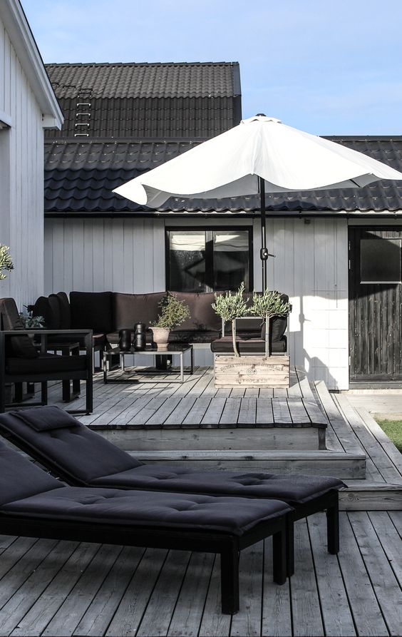 a stylish Scandinavian terrace with a black sofa, chair and loungers, an umbrella and a coffee table is all cool a stylish Scandinavian terrace with a black sofa, chair and loungers, an umbrella and a coffee table is all cool