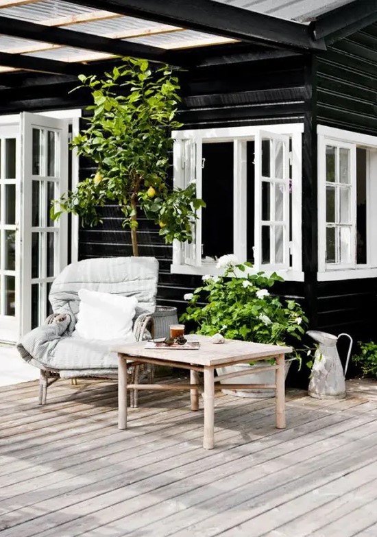 a summer Nordic terrace with rattan furniture, cozy neutral upholstery, potted greenery and a large tree a summer Nordic terrace with rattan furniture, cozy neutral upholstery, potted greenery and a large tree