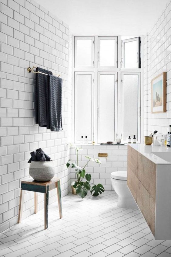 a welcoming Scandi bathroom with vintage touches, a wooden vanity =, towels and a large window for natural light