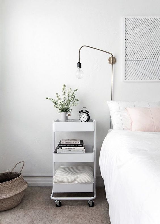 a white tiered cart on casters is an amazing piece for a Scandinavian bedroom, it features a lot of storage space and is mobile