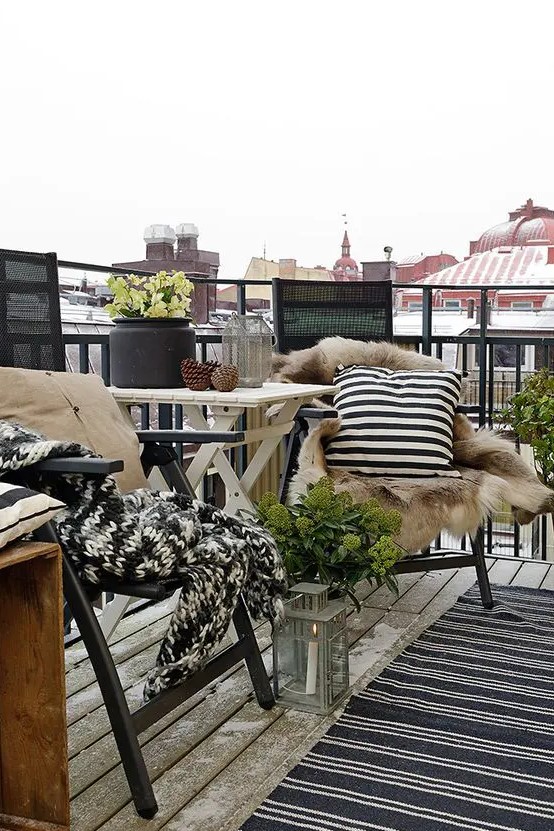 a wooden coffee table, a couple of metal chairs, candle lanterns and rugs plus faux fur for coziness