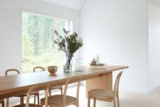 an airy Scandinavian dining space with a stained table and chairs, with a view of the forest is a lovely idea