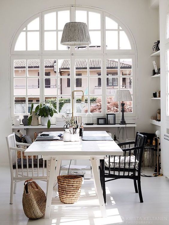 an airy Scandinavian home office with a white desk, a black and white chair, a pendant lamp, baskets and lamps is amazing