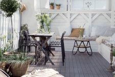 an inviting Scandinavian terrace with a dark dining set, a built-in whit bench, a hairpin leg table and rattan loungers