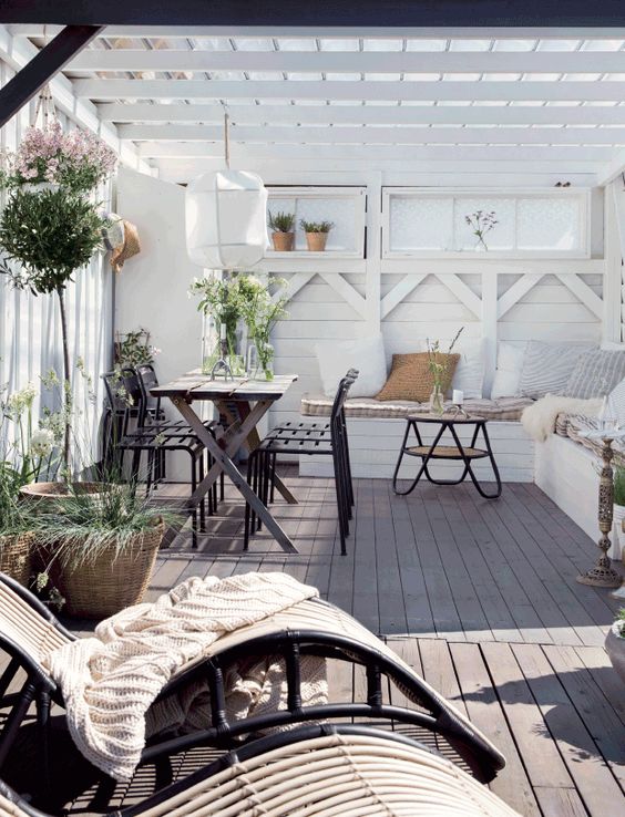an inviting Scandinavian terrace with a dark dining set, a built in whit bench, a hairpin leg table and rattan loungers an inviting Scandinavian terrace with a dark dining set, a built-in whit bench, a hairpin leg table and rattan loungers