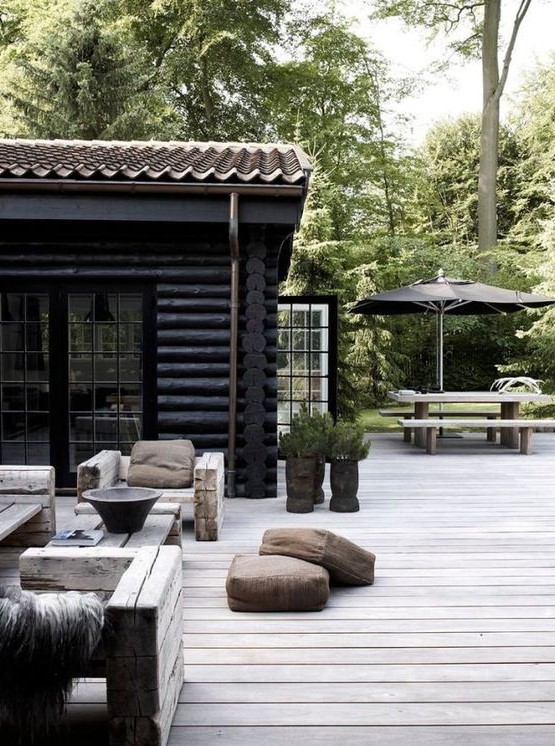 an outdoor Nordic space with wood beam furniture, potted greenery and leather floor cushions