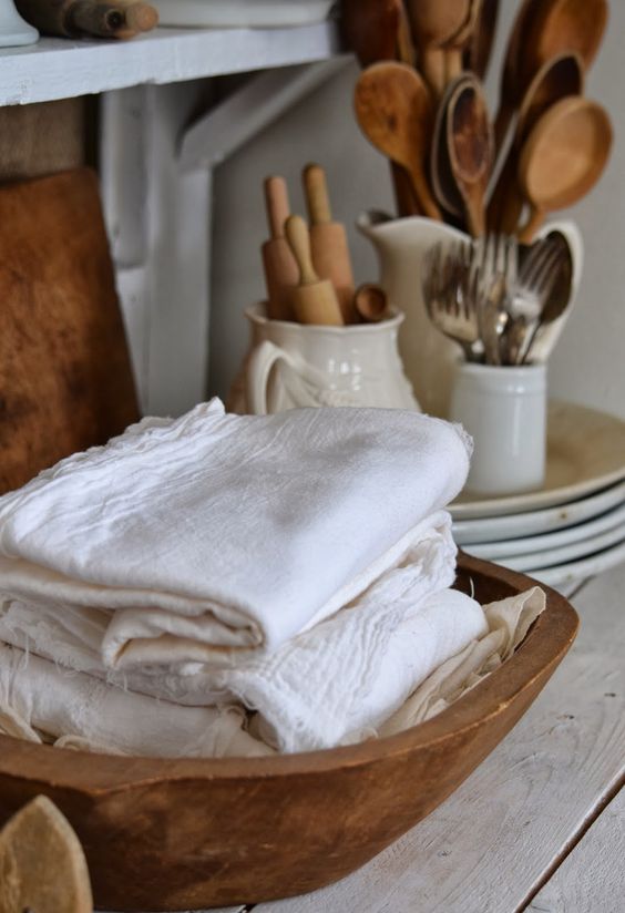 kitchen towels stored in a vintage dough bowl is a cool idea for a rustic kitchen