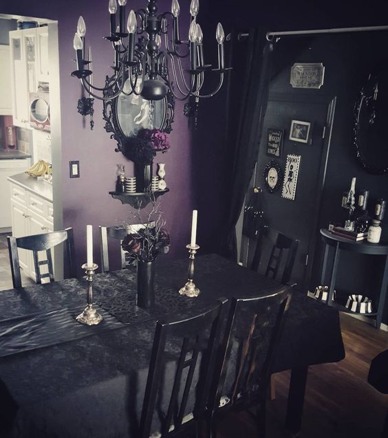 a Gothic dining space with black and purple walls, black furniture, an oversized mirror, a vintage-styled chandelier