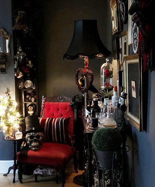 a Gothic living room with black walls, a refined red chair, skulls and a chic gallery wall is striking