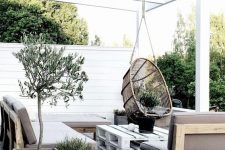 a Scandinavian terrace with concrete planters, wooden and pallet furniture and a hanging rattan chair