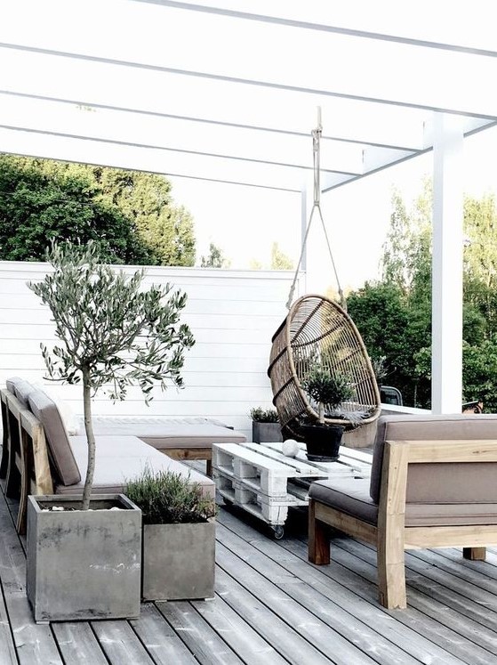 a Scandinavian terrace with concrete planters, wooden and pallet furniture and a hanging rattan chair