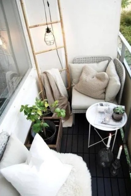 a black and white balcony with two comfy wicker seats, a coffee table, candles and a ladder for storage