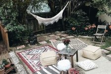 a boho Moroccan outdoor space with printed rugs and ottomans, with a hammock and string lights over the space