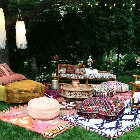 a boho lounge with printed rugs, ottomans and upholstery and tassels hanging