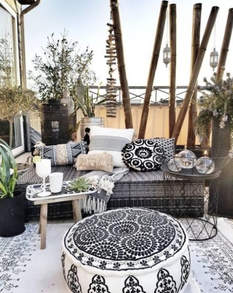 a boho monochromatic terrace with a Moroccan feel, an upholstered bench, pillows and ottomans plus potted greenery