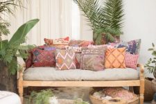 a boho terrace with light-stained furniture, colorful printed pillows, low coffee tables, potted greenery and candles