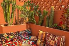 a bold Moroccan terrace with colorful rugs and cushions, low coffee tables and large cacti growing there