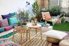 a bold boho terrace with super colorufl pillows and cushions, layered rugs, rattan coffee tables and potted plants