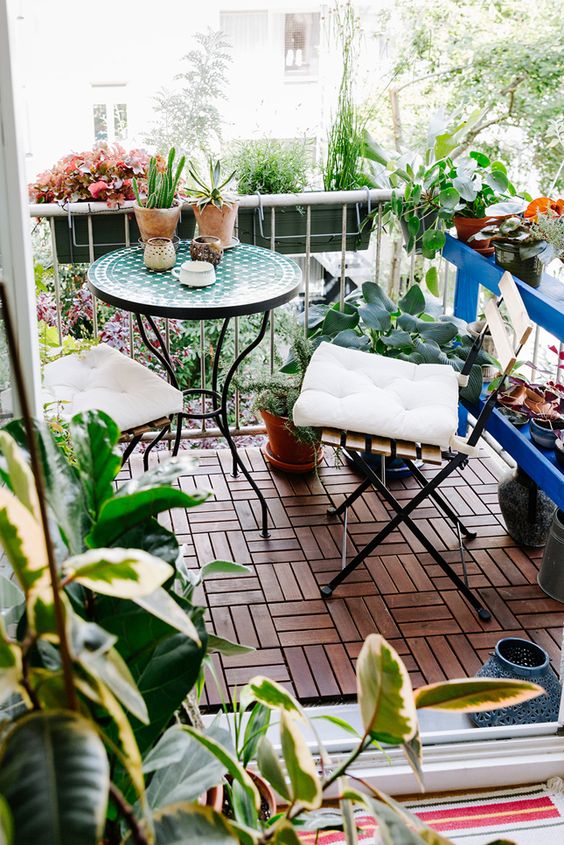 a bright balcony with a coffee table and folding chairs, potted greenery and blooms is a cool and bold space