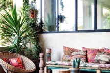 a bright desert boho terrace with wicker and wooden furniture, potted cacti and greenery hanging and bright textiles